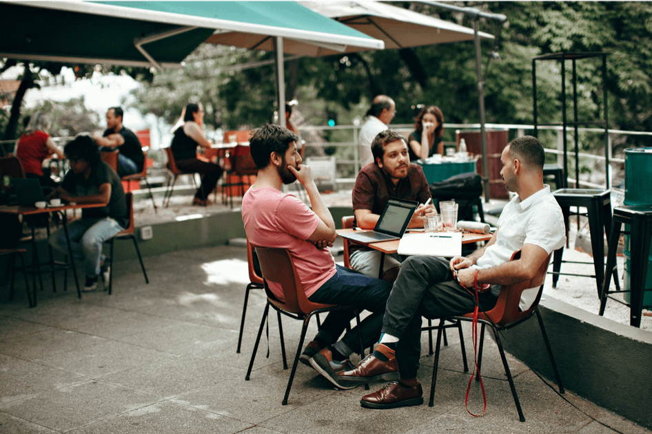 People sitting at a cafe with laptop and notebooks
